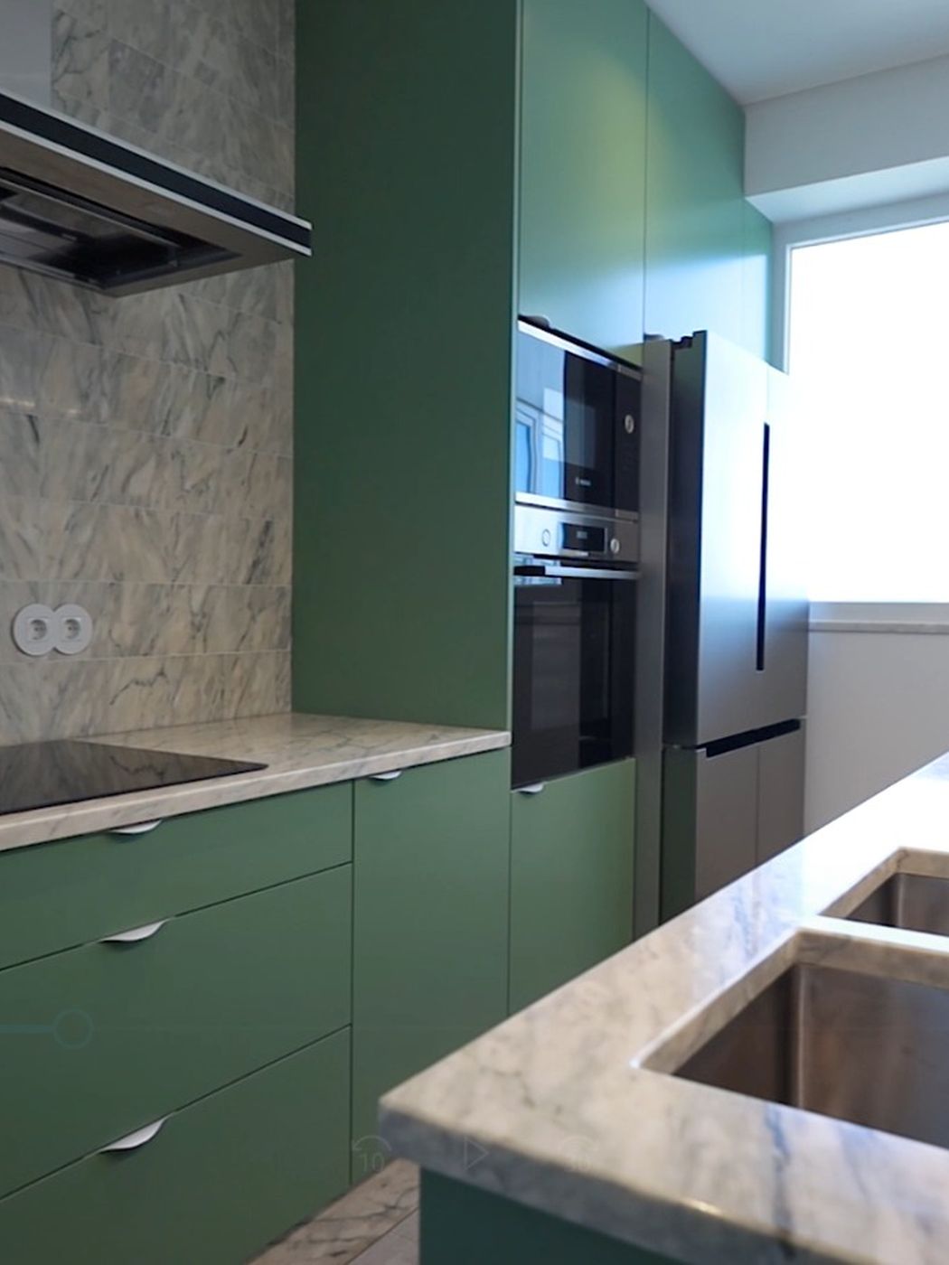 Cozinha com móveis verdes, bancada em pedra e eletrodomésticos encastrados, em Setúbal